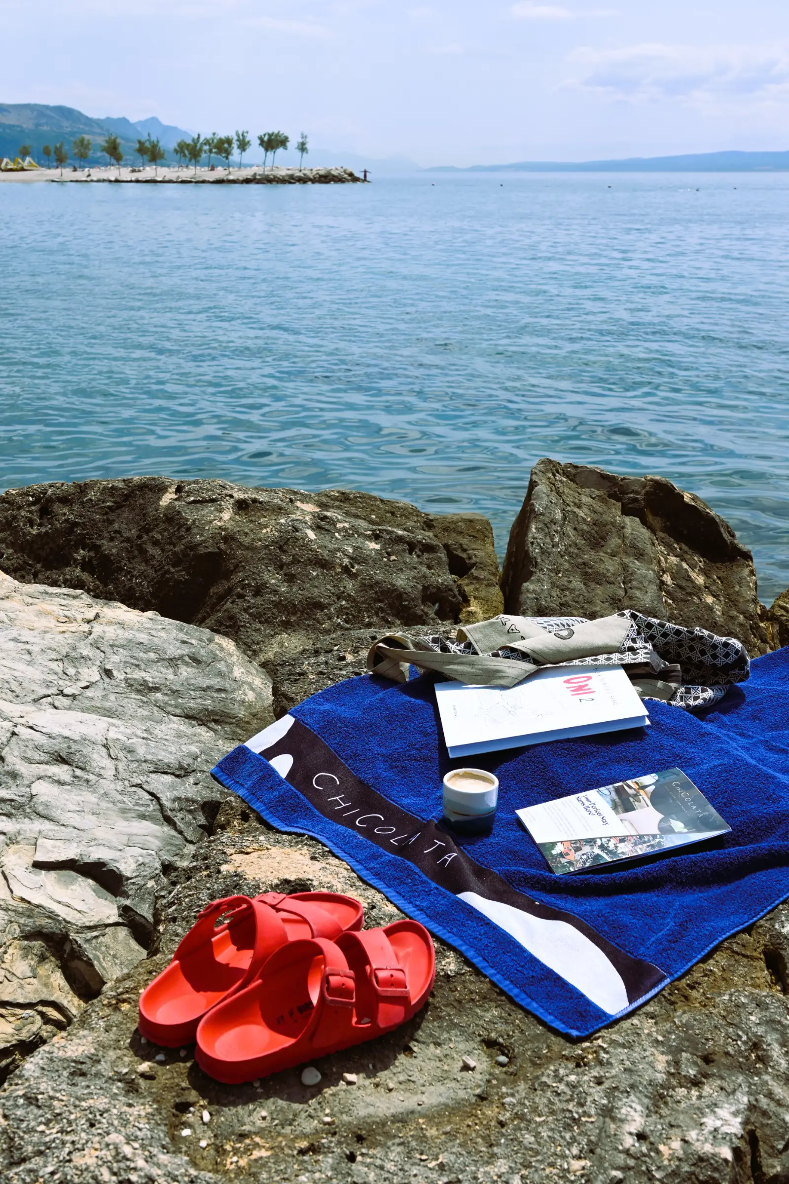 ChiColata beach towel, guide and coffee on the rocks by the sea in Split