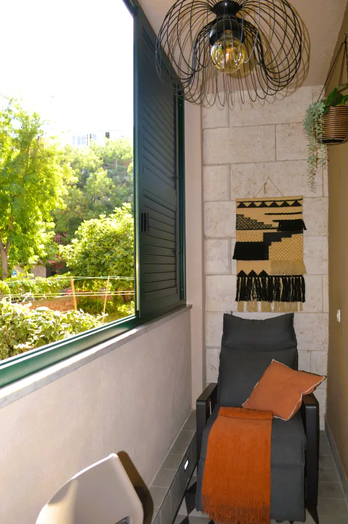 A bench on the balcony beside the green shutters